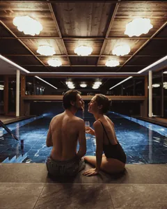 Paar sitzt am Beckenrand des Panorama-Skypool im Terentnerhof mit Sektglas in der Hand und lächelt sich an