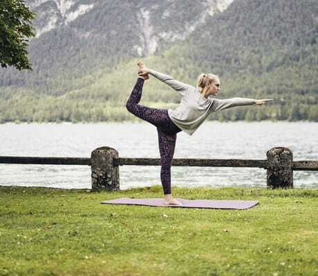 blonde Frau macht Yoga direkt am Ufer des Travel Charme Fürstenhaus am Achensee