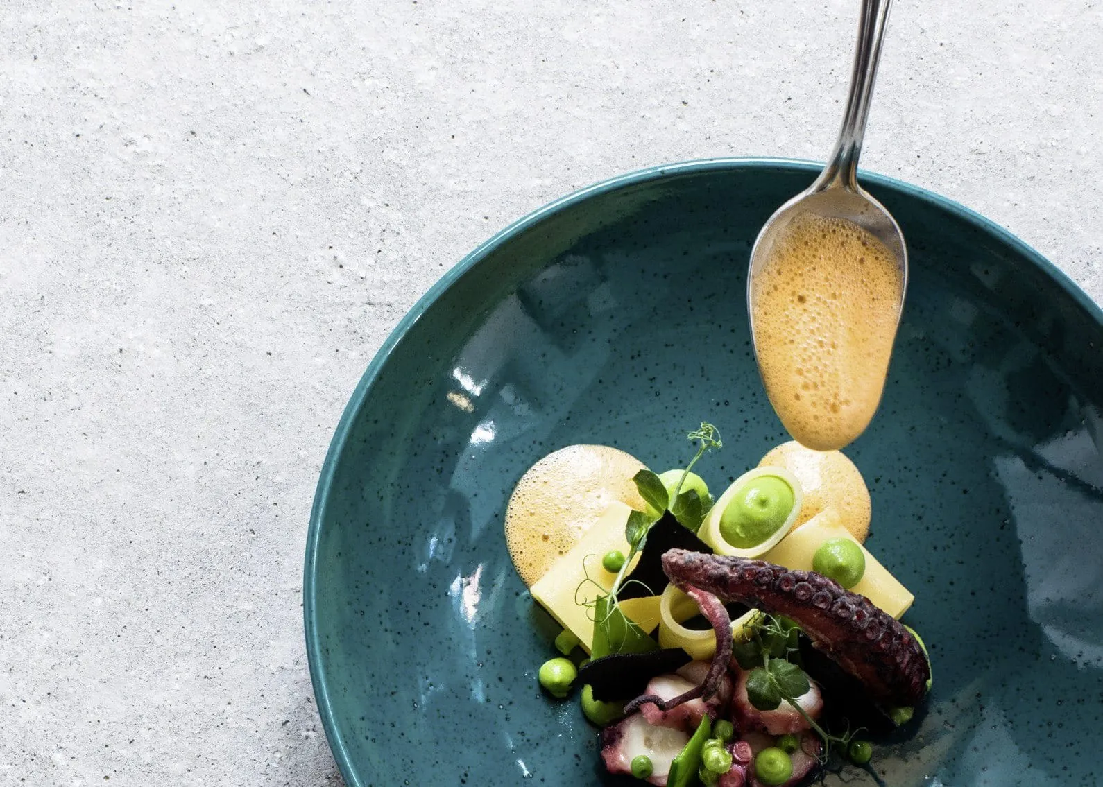 Gericht mit Tintenfisch auf türkisem Teller im Hotel Weisses Kreuz