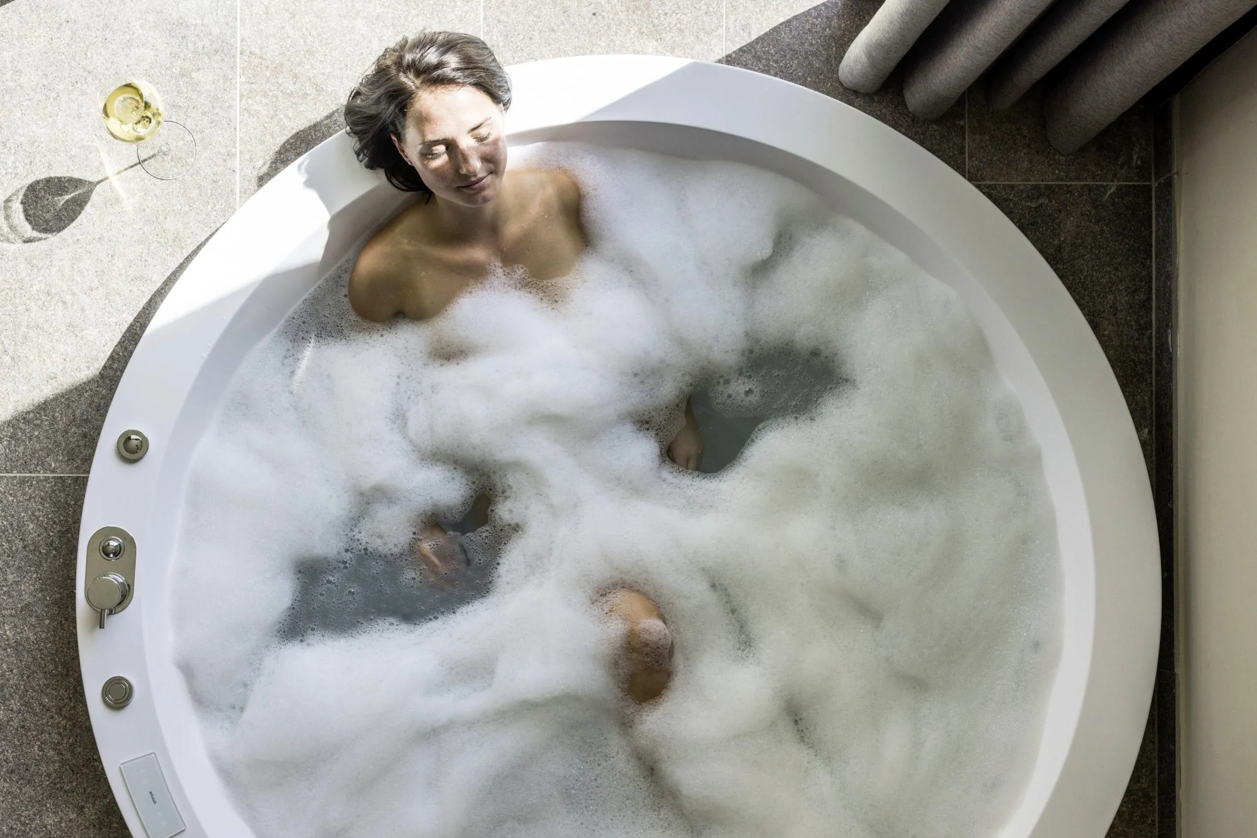 dunkelhaarige Frau liegt im runden Whirlpool des Hotel Weisses Kreuz im Schaumbad