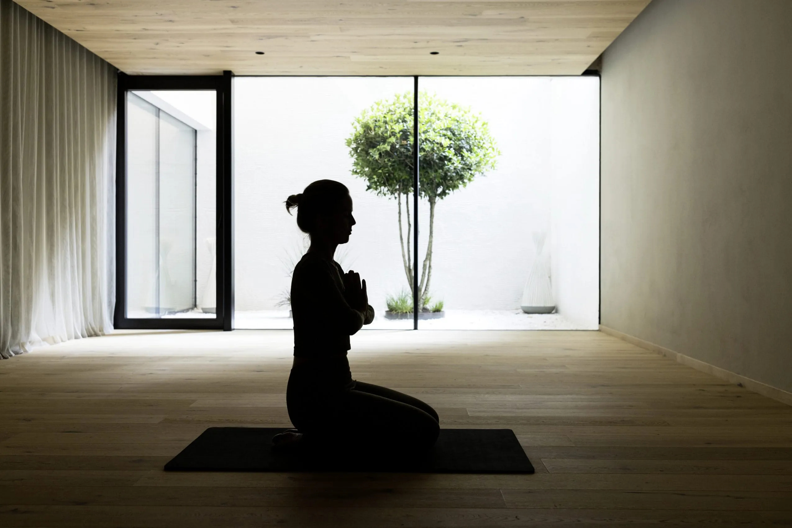 Schatten einer sitzenden Frau, die Yoga im Yogaraum des Hotel Weisses Kreuz praktiziert