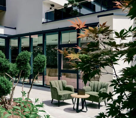 Innenhof im Das SeeMOUNT mit grünen Sesseln und Ahornbaum