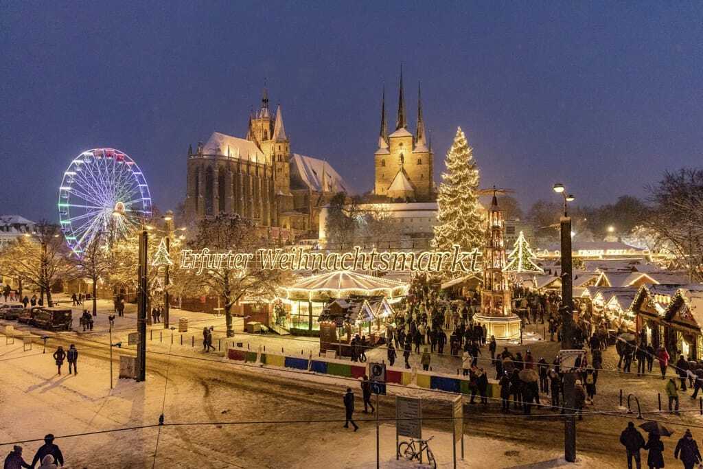 Gesamtansicht des Erfurter Weihnachtsmarktes mit Riesenrad, Pyramide, Tannenbaum, Dom und Severikirche am Abend mit Schnee