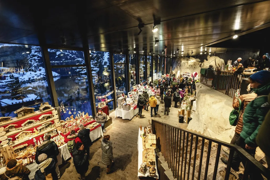 Einige Menschen st&ouml;bern an St&auml;nden des weihnachtlichen Indoor-Marktes "Granitweihnacht" mit Blick auf einen See