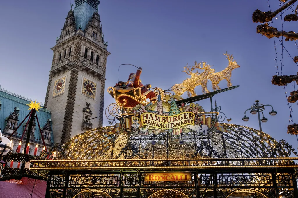 Weihnachtsdekoration Weihnachtsmann mit leuchtenden Rentieren auf einer gro&szlig;en Lichtinstallation des Hamburger Weihnachtsmarktes mit Rathausturm im Hintergrund