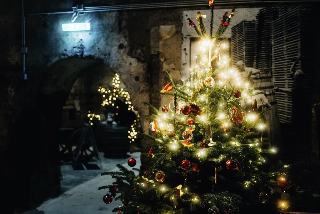 Mit Lichtern und verschiedenen Kugeln geschm&uuml;ckter Tannenbaum in einem dunklen Gew&ouml;lbekeller des Mosel-Wein-Nachts-Marktes in Traben Trarbach
