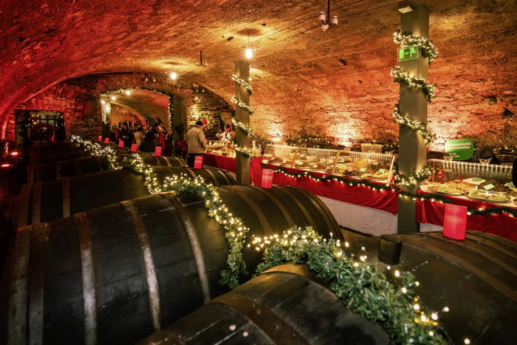 Weinkellergew&ouml;lbe auf dem Mosel-Wein-Nachts-Markt mit mit Lichterketten geschm&uuml;ckten Weinf&auml;ssern und Marktst&auml;nden