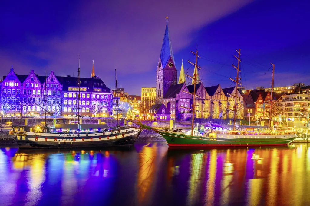 Beleuchtete Schiffe vor historischen Geb&auml;uden an einem Flussufer in Bremen