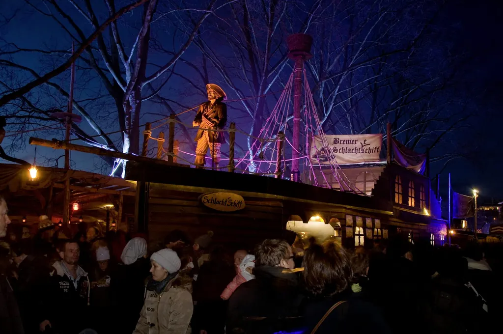 Piratenschiff-Nachbau mit Piratenfigur und vielen Menschen bei Abendstimmung auf dem Schlachte-Zauber in Bremen