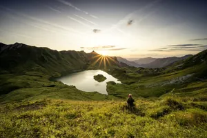 Mann sitzt in der Abendsonne auf einer Wiese am Schrecksee