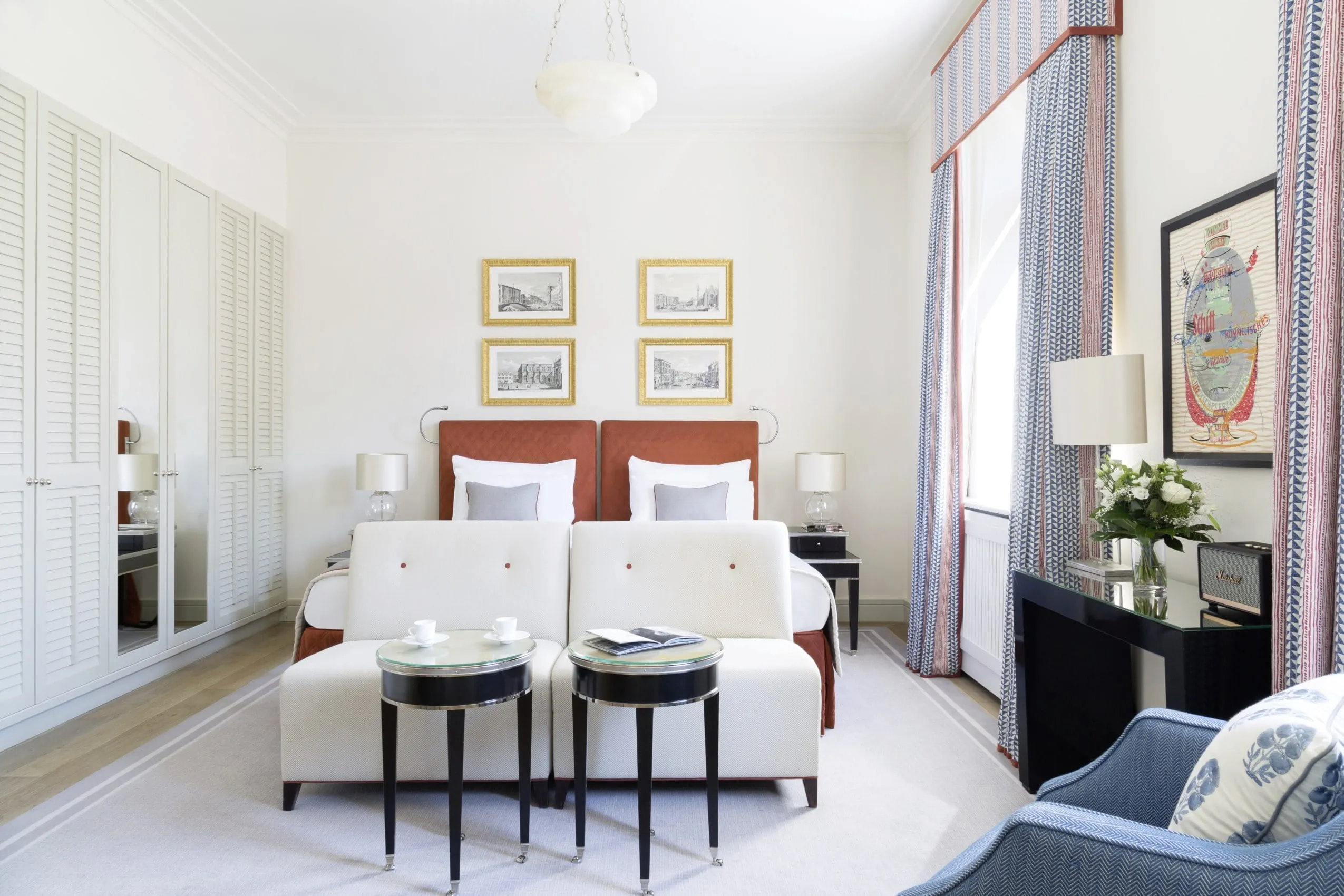 Gro&szlig;es helles Zimmer, mit wei&szlig;en M&ouml;beln, wei&szlig;en Sesseln und wei&szlig;er Bettw&auml;sche. Hellblaue bodenlange Vorh&auml;nge geben kleine Farbakzente.