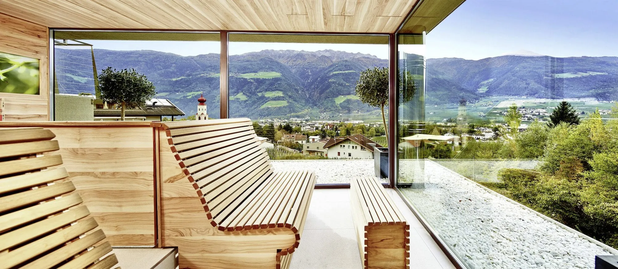 Sauna mit zwei riesen Glas-Panoramaw&auml;nden und Blick auf die umliegende Landschaft mit D&ouml;rfern, Wiesen und Bergen.