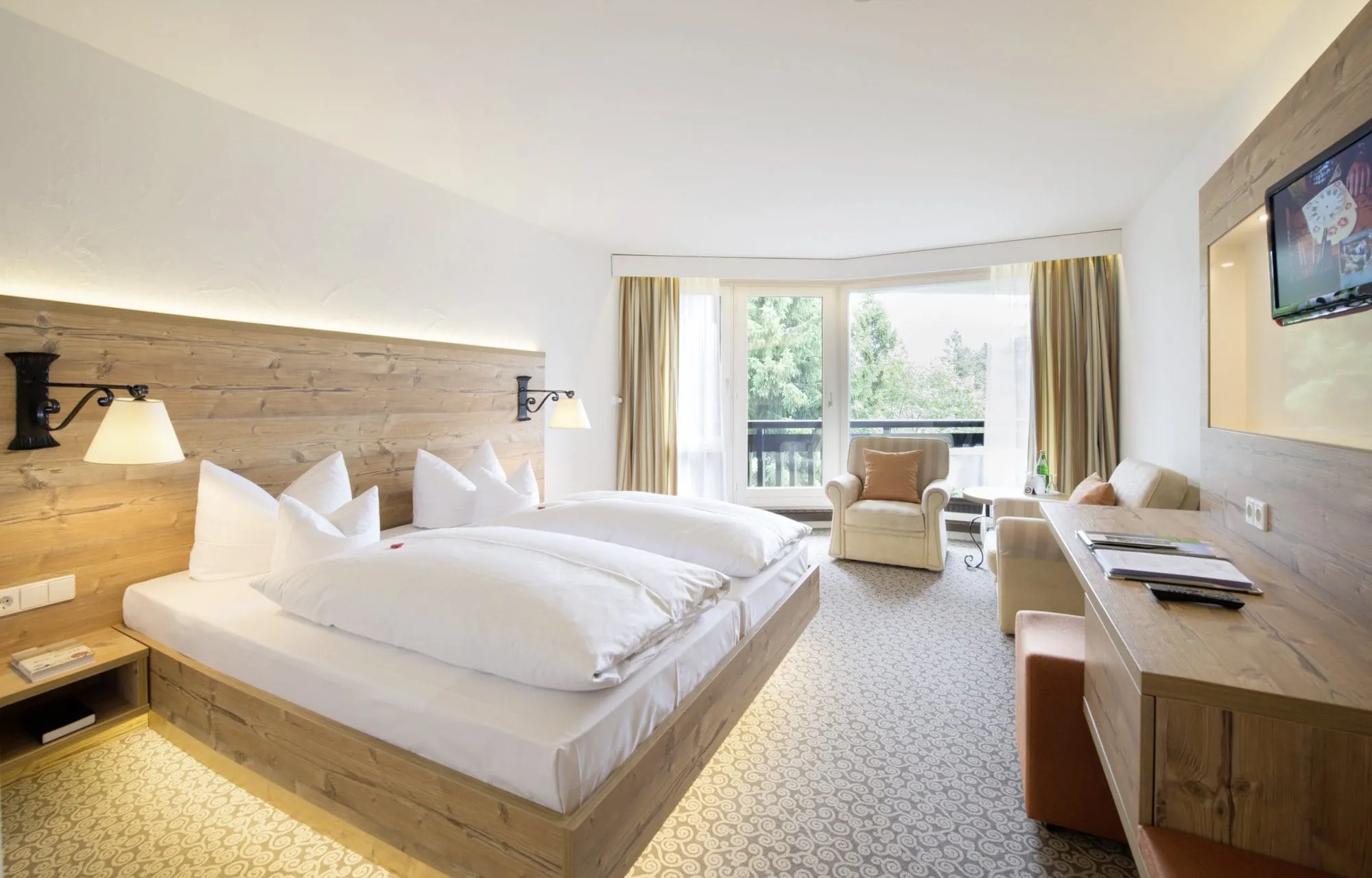 Zimmer mit Schn&ouml;rkel gemustertem beigen Teppichboden, Kingsize Doppelbett mit Massivholzverkleidung.