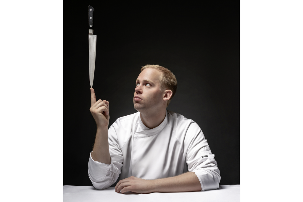 Küchenchef Manuel Ulrich balanciert ein Messer auf seinem Finger