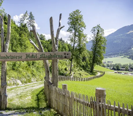 Eingang mit Holzschild zur Hundewiese des Gartenhotel Magdalena mit Holzzaun