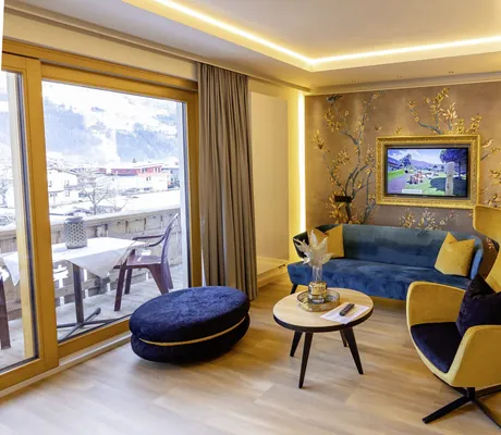 Suite im Gartenhotel Magdalena mit gelbem Ohrensessel und dunkelblauem Sofa