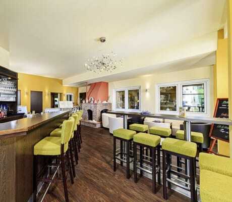 Bar im Vitalhotel Sonneck mit Kamin und grünen Hochstühlen