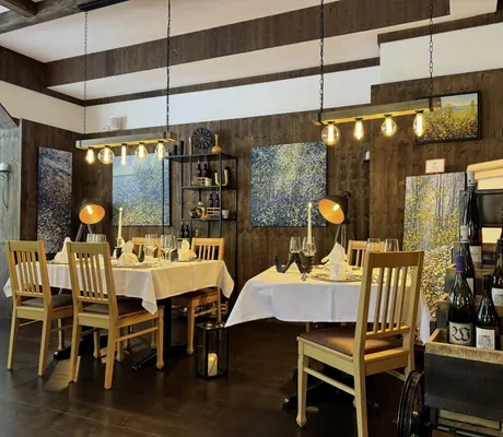 Restaurant im Vitalhotel Sonneck mit Blätterbildern an den Wänden und Wagen mit Weinflaschen