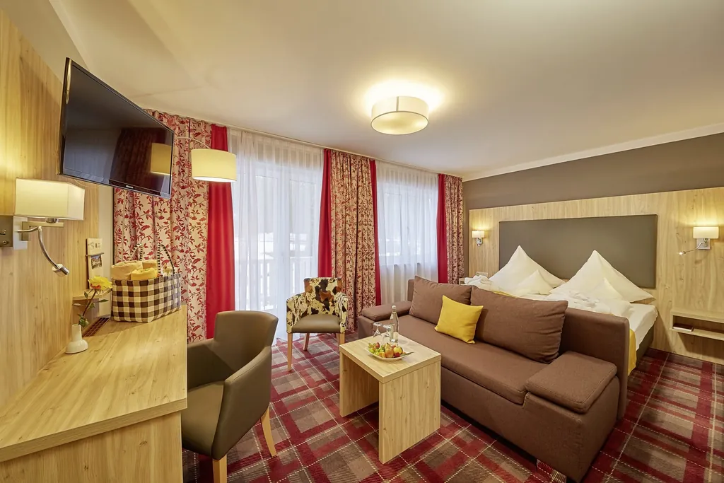 Zimmer im Vitalhotel Sonneck mit kariertem Teppich und roten Vorhängen