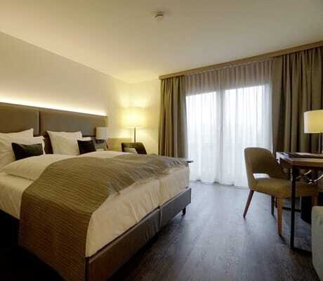 Zimmer im Flair Park-Hotel Ilshofen mit beigem Bettüberwurf und Stoff-Rückwand