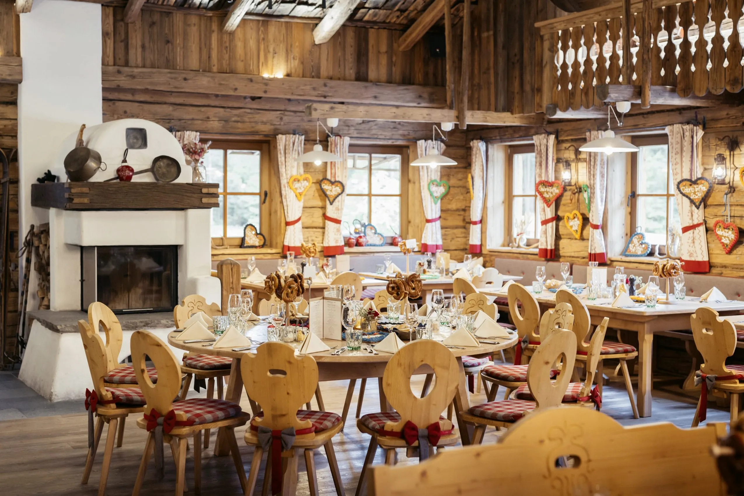 bayerisch eingedeckte Tische in der Interalpen-Alm mit Kaminofen und karierten Sitzkissen