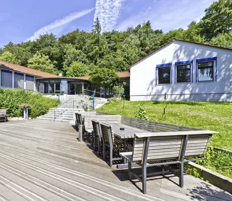 Außenbereich mit Sitzecken mit Holzbänken und Blick auf den Eingang des Seminarzentrum Rückersbach