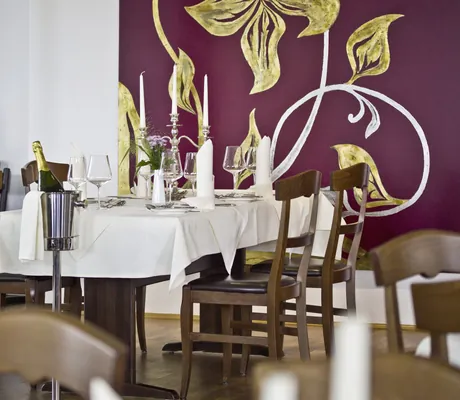 gedeckter Tisch vor burgunderrot gestrichener Wand im Restaurant des Seminarzentrum Rückersbach