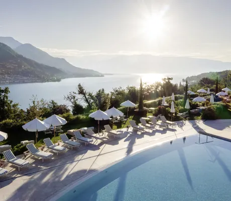 Outdoorpool mit weißen Sonnenschirmen des A-ROSA Lago di Garda auf einem Plateau mit Blick auf den Gardasee