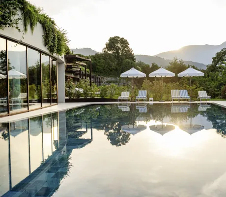 Spa-Pool mit weißen Sonnenschirmen und Blick auf die Berge im A-ROSA Lago di Garda