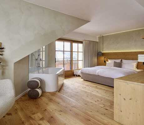 Renovierte Suite mit freistehender Badewanne, Balkon und Doppelbett im Wellnesshotel HUBERTUS Mountain Refugio Allgäu