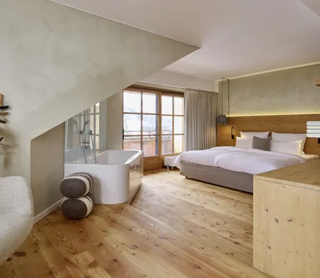 Renovierte Suite mit freistehender Badewanne, Balkon und Doppelbett im Wellnesshotel HUBERTUS Mountain Refugio Allgäu
