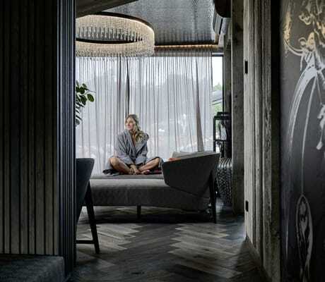 blonde Frau sitzt im Schneidersitz auf einer Chaiselongue im Ruherraum des Hotels die Hochkönigin