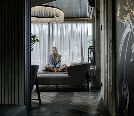 blonde Frau sitzt im Schneidersitz auf einer Chaiselongue im Ruherraum des Hotels die Hochkönigin