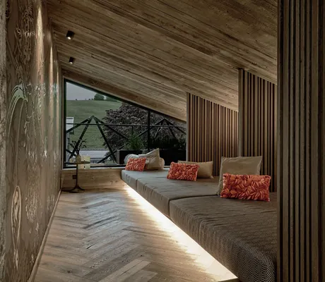 Ruhekojen unter dem schrägen Holzdach des Hotels die Hochkönigin mit roten Kissen