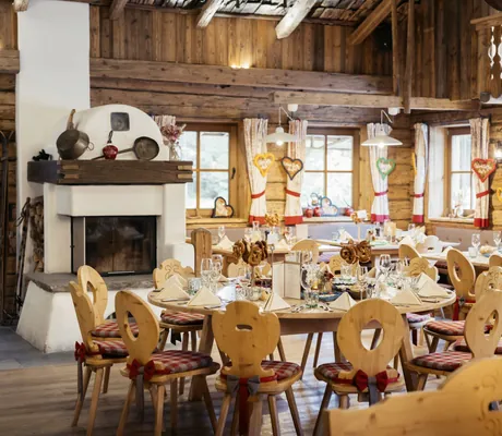 bayerisch eingedeckte Tische in der Interalpen-Alm mit Kaminofen und karierten Sitzkissen