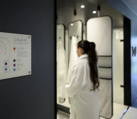 dunkelhaarige Frau mit Zopf betritt die Kältekammer im Interalpen-Hotel Tyrol