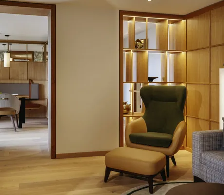 Sitzecke mit Ohrensessel vor Holzregal in der Suite des Interalpen-Hotel Tyrol