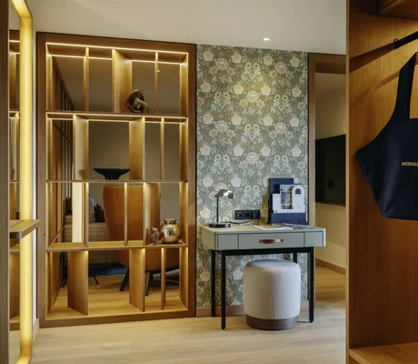 Holzregal im Gang mit Blumentapete und Schreibtisch in der Suite des Interalpen-Hotel Tyrol