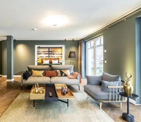 Wohnraum im Palais Kayser des Jugendstilhotel Bellevue mit grauen Sitzmöbeln und Blumenarrangement auf Holzblock