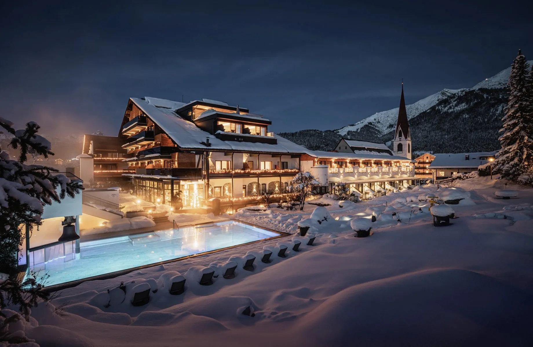 Außenansicht des Hotel Klosterbräu im tiefen Schnee mit beleuchtetem Außenpool