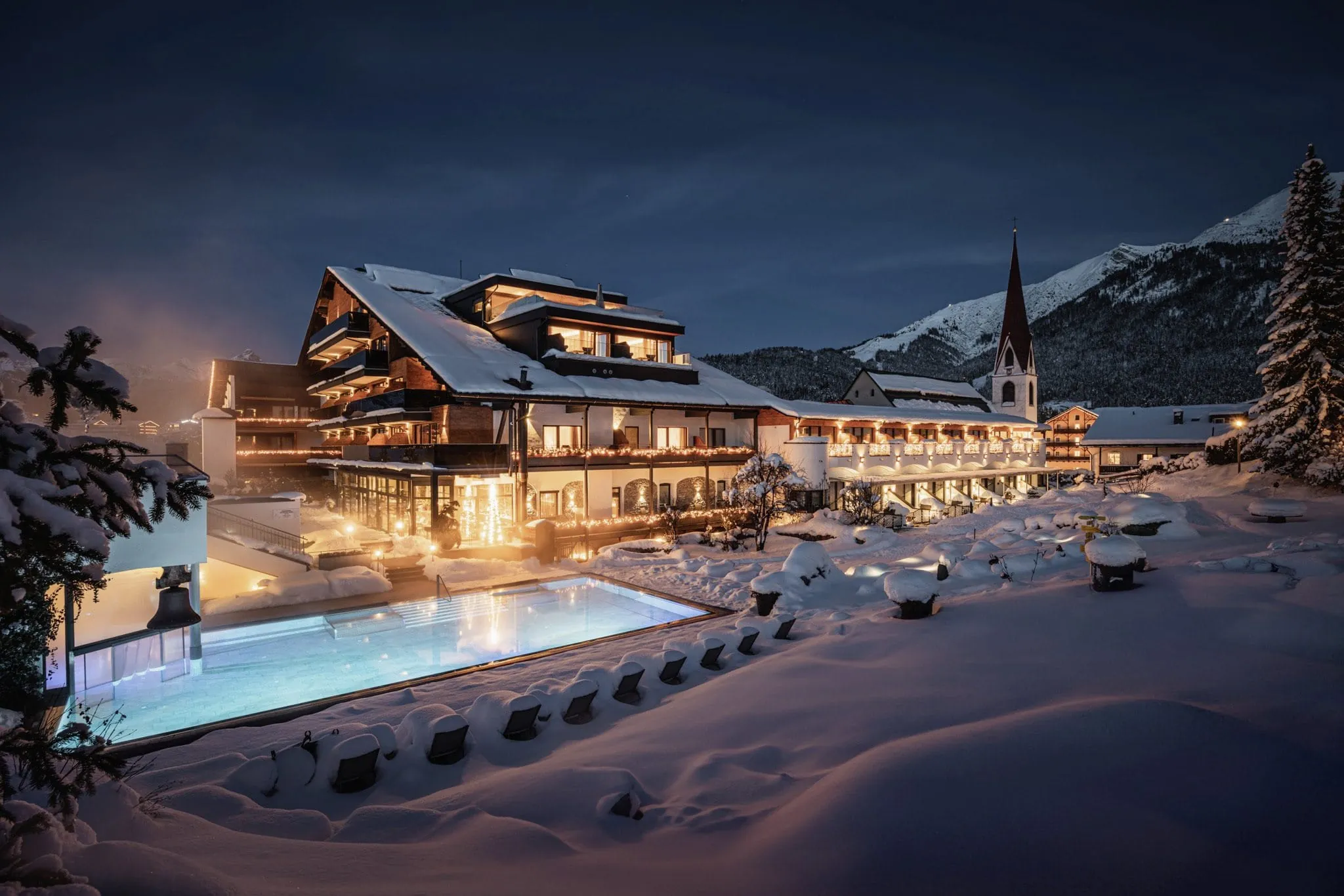 Außenansicht des Hotel Klosterbräu im tiefen Schnee mit beleuchtetem Außenpool