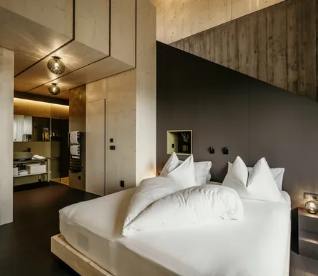 Zimmer mit hoher Decke und Bett mit Decken in Herzform im Hotel Pfösl