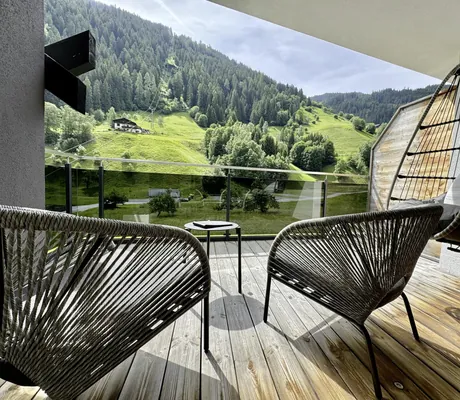 Zimmerbalkon im Das SeeMOUNT mit Hängekorbsessel und Korbstühlen mit Blick auf den Hang