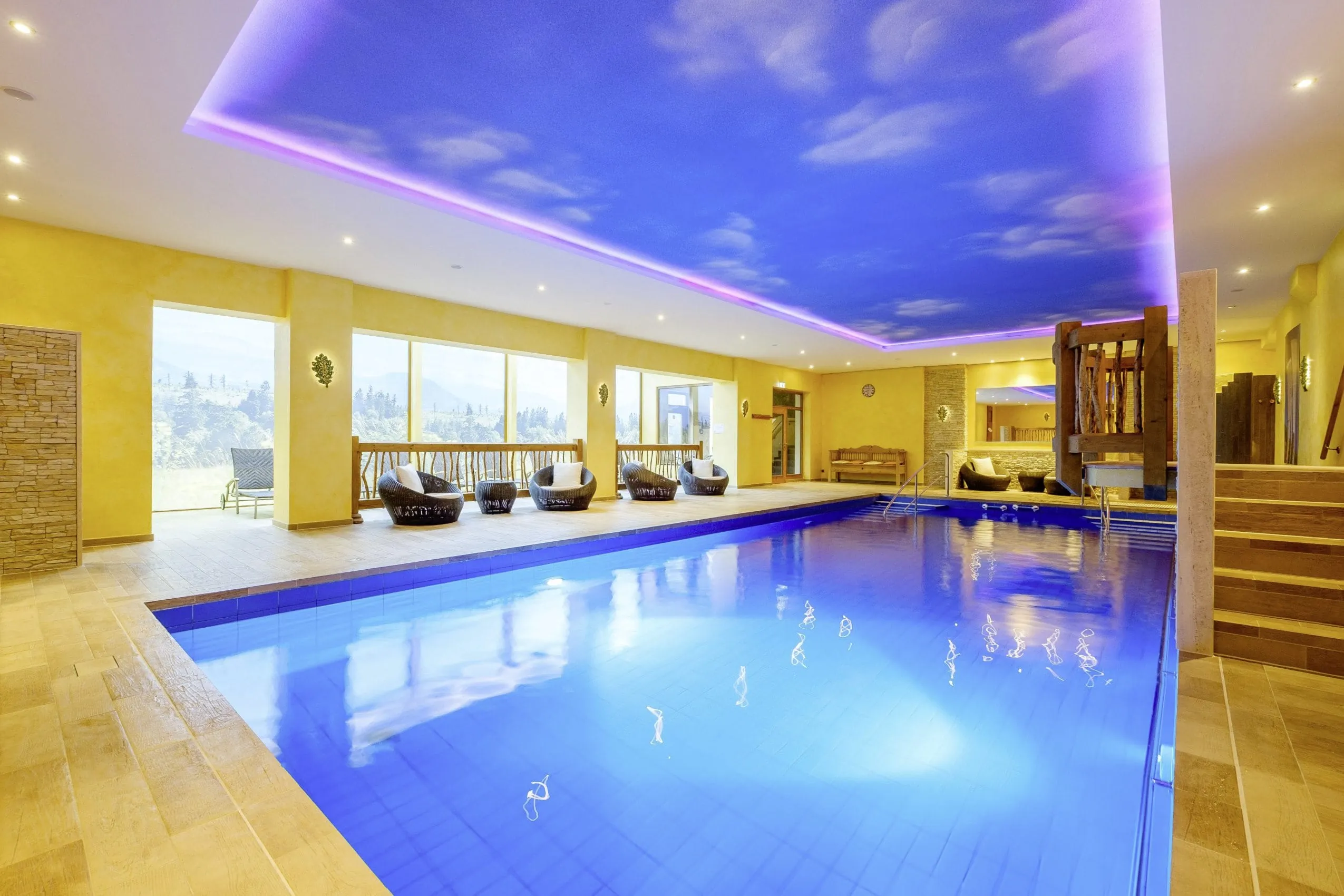 Beleuchteter Indoorpool im Wellnesshotel Tanne mit Korbsesseln