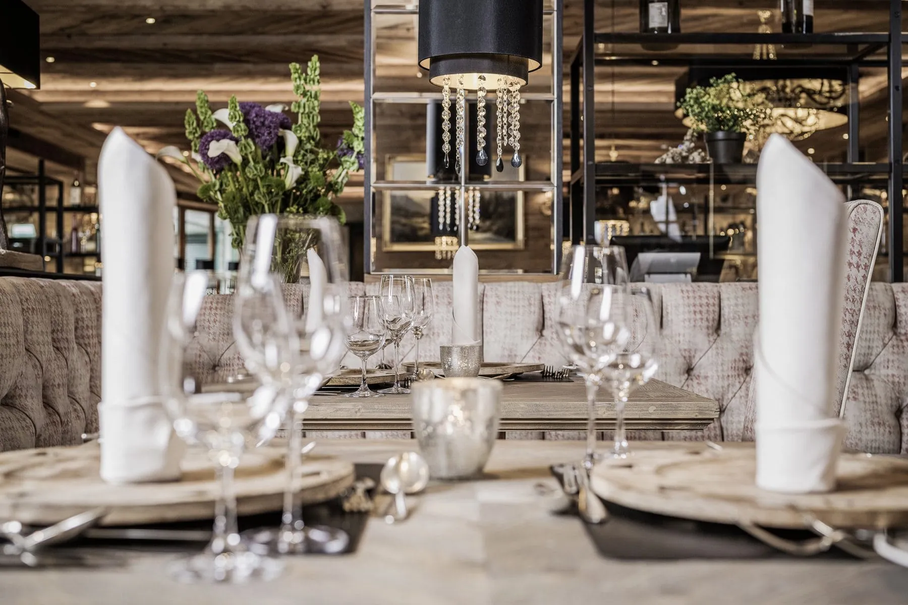 Edel gedeckter Tisch mit Weingl&auml;sern, Silberbesteck und gro&szlig;en wei&szlig;en Stoffservietten im modern eingerichteten Restaurant des Alpin Resort Sacher.