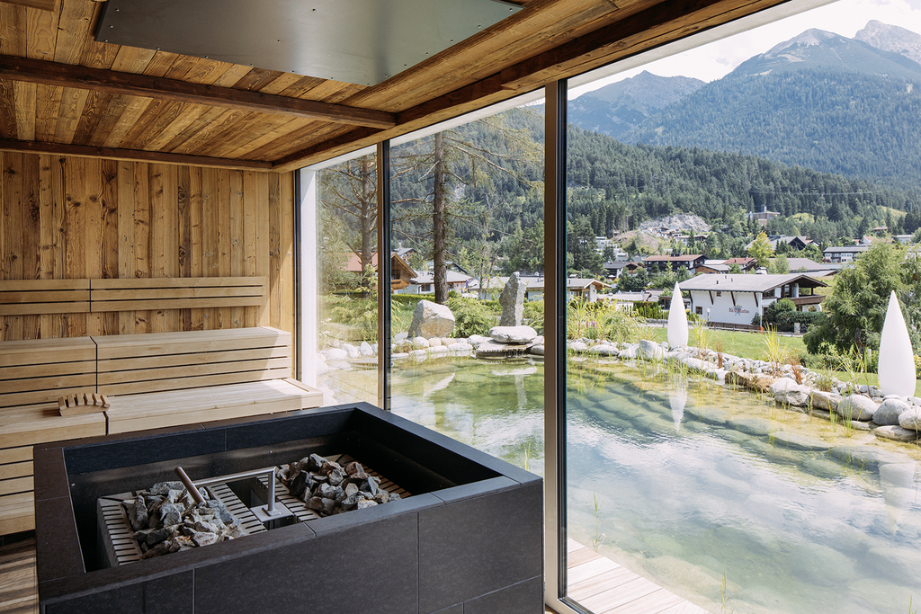 Große Panoramafenster in der Sauna des Alpin Resort Sacher gewähren einen herrlichen Ausblick auf Naturteich und Bergpanorama.