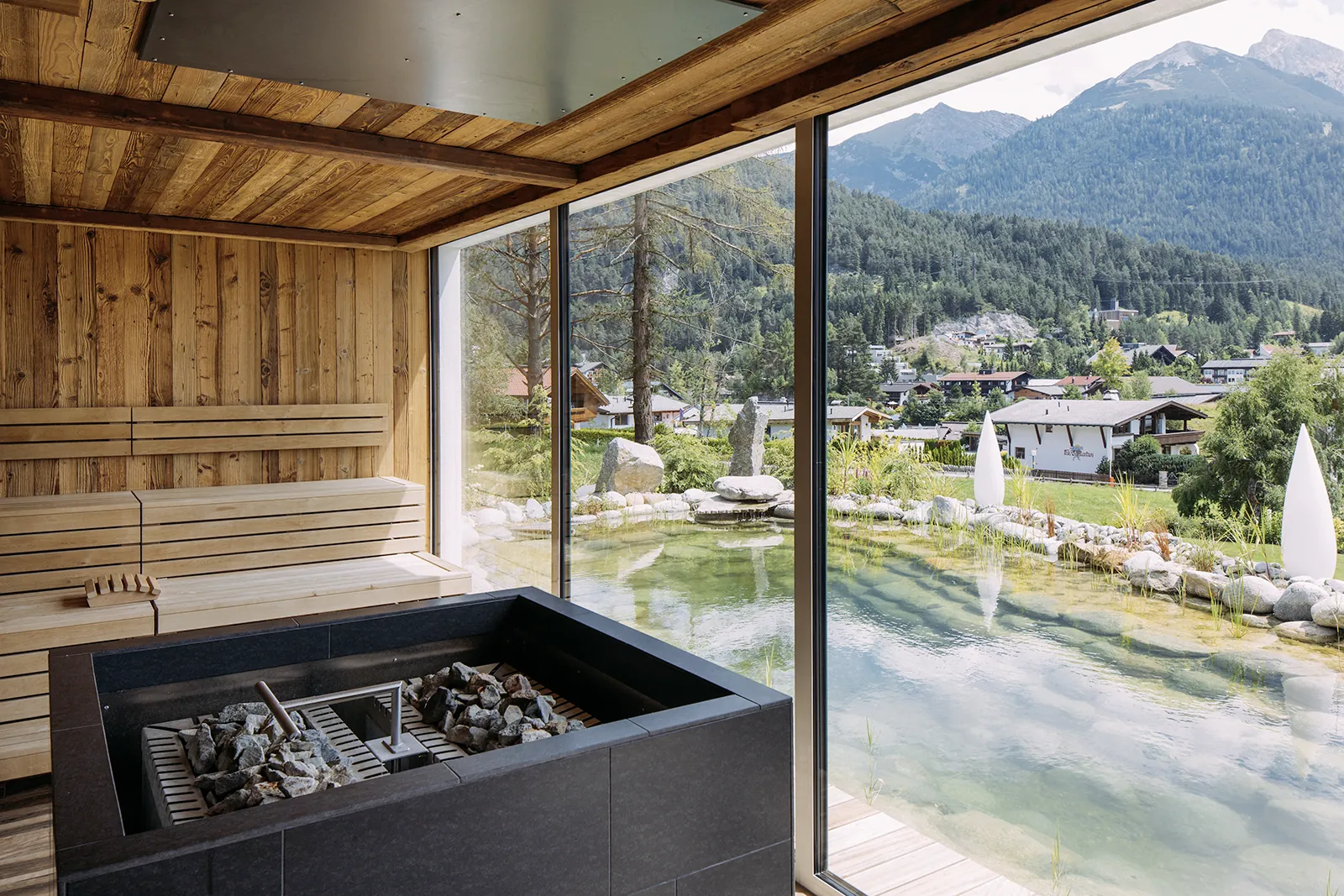 Gro&szlig;e Panoramafenster in der Sauna des Alpin Resort Sacher gew&auml;hren einen herrlichen Ausblick auf Naturteich und Bergpanorama.