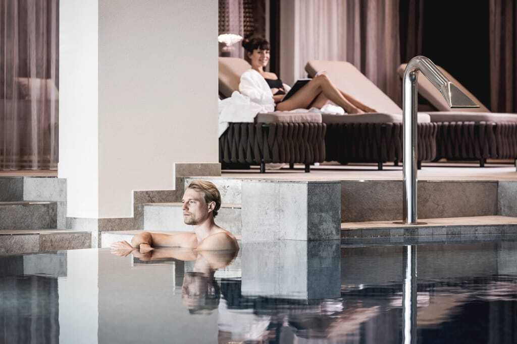 Wellnessbereich des Krumers Alpin mit Pool und Liegenbereich in moderner Betonsteinoptik
