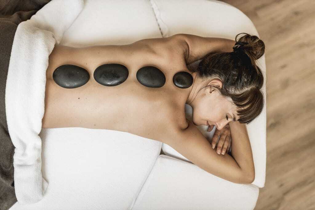 Frau bei einer Hot Stone Wellnessbehandlung im Tiroler Wellnesshotel Krumers Alpin