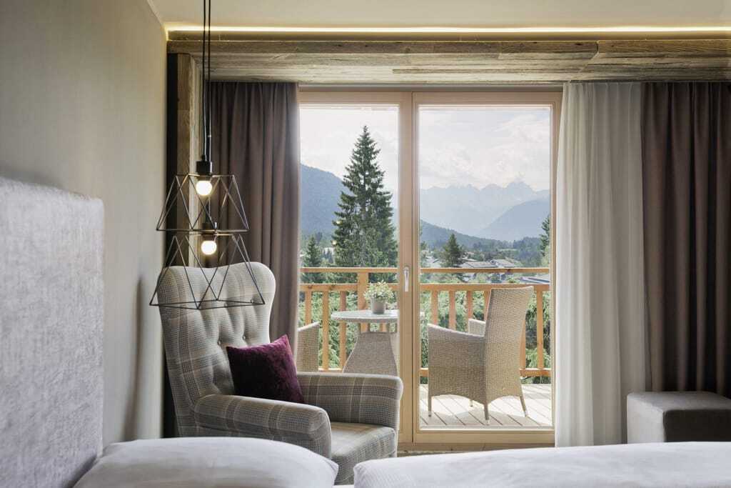 Blick vom einem Zimmer des Wellnesshotels Lärchenhof auf den Balkon und die Berglandschaft im Hintergrund.